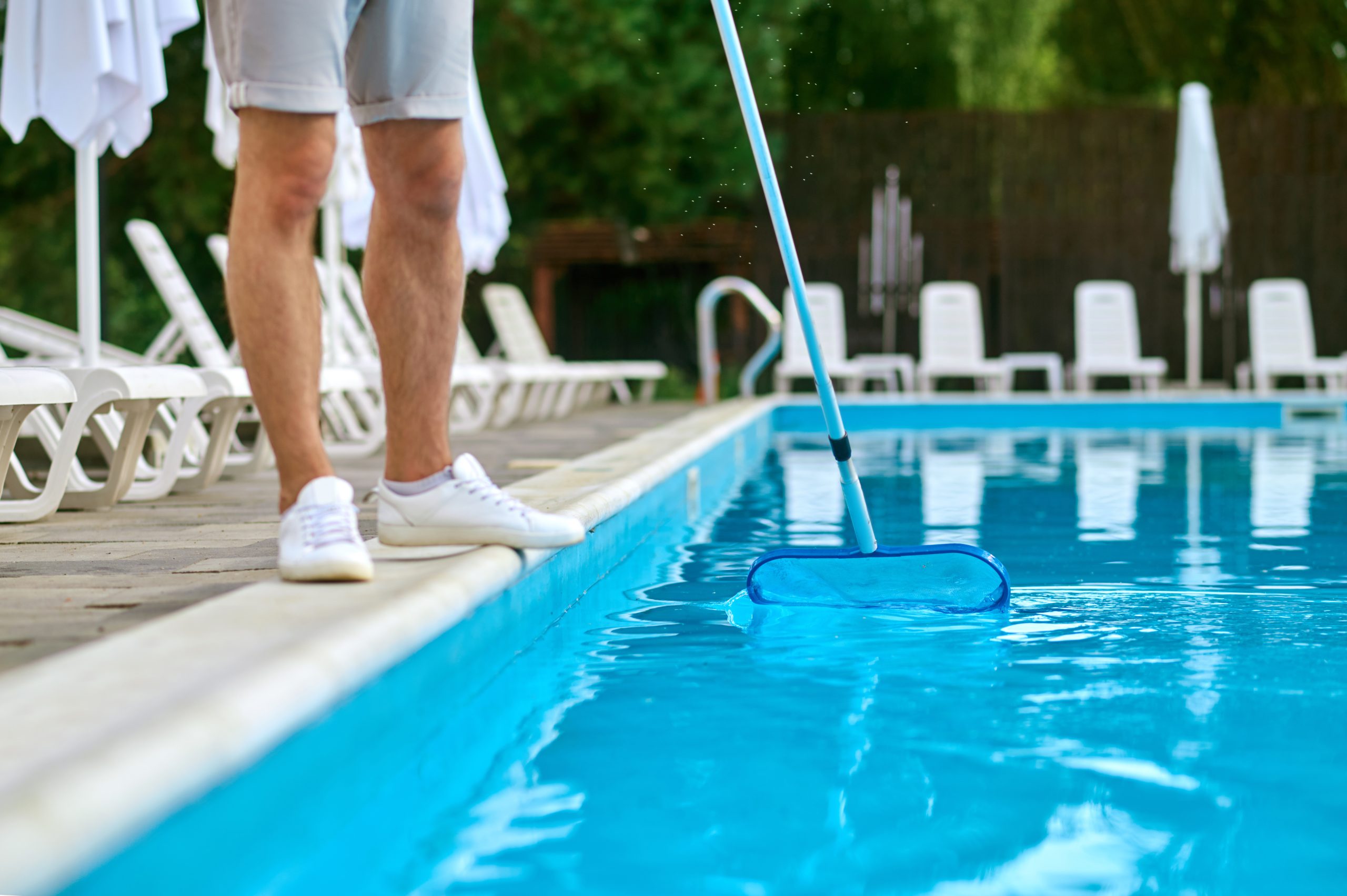 Man maintaining a pool removing debris and pool heater repair for pool care